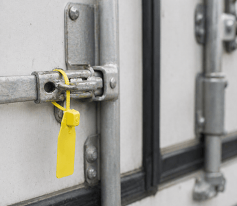 Tamper evident seal from JW Products applied to trailer door latch, showing intact seal for logistics chain of custody and cargo protection
