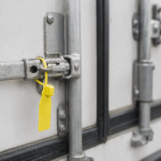 Tamper evident seal from JW Products applied to trailer door latch, showing intact seal for logistics chain of custody and cargo protection