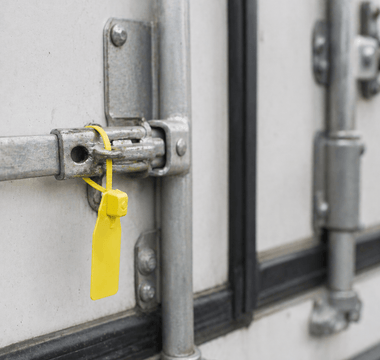 Tamper evident seal from JW Products applied to trailer door latch, showing intact seal for logistics chain of custody and cargo protection
