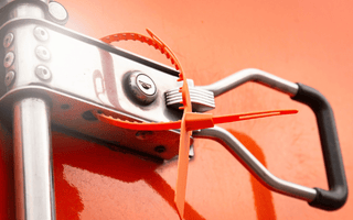 Close-up of a metal handle on a red truck, emphasizing the importance of tamper seals for safety equipment checks.