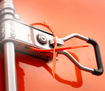 Close-up of a metal handle on a red truck, emphasizing the importance of tamper seals for safety equipment checks.