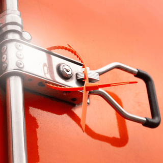 Close-up of a metal handle on a red truck, emphasizing the importance of tamper seals for safety equipment checks.
