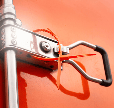 Close-up of a metal handle on a red truck, emphasizing the importance of tamper seals for safety equipment checks.