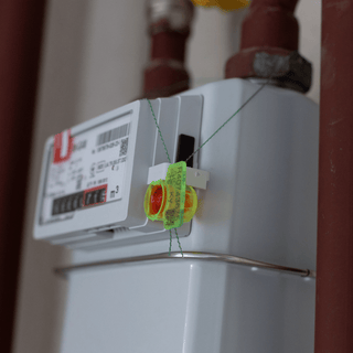  A water meter securely attached to a pipe, featuring a visible seal tag for security purposes