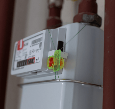  A water meter securely attached to a pipe, featuring a visible seal tag for security purposes