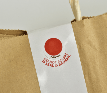 A brown paper bag featuring a prominent red tamper-proof sticker for security and authenticity.