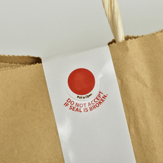 A brown paper bag featuring a prominent red tamper-proof sticker for security and authenticity.