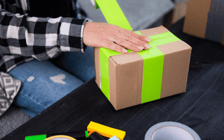 Applying tamper tape around a box, ensuring the contents remain sealed for event equipment hire.