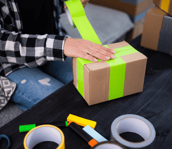 Applying tamper tape around a box, ensuring the contents remain sealed for event equipment hire.