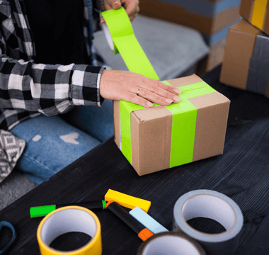 Applying tamper tape around a box, ensuring the contents remain sealed for event equipment hire.