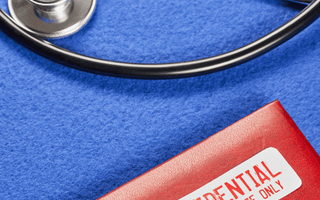 A stethoscope beside a red folder labeled "Confidential," featuring a tamper-evident seal for medical records security.