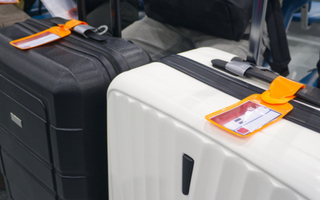 A classic black and white suitcase featuring a patterned design, positioned upright against a neutral background.