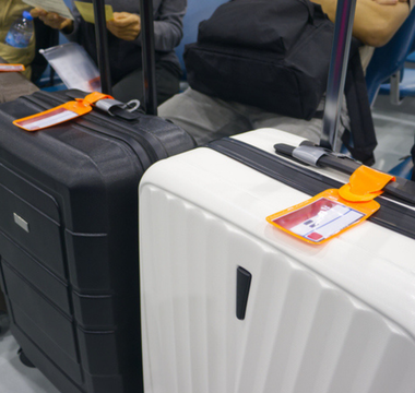 A classic black and white suitcase featuring a patterned design, positioned upright against a neutral background.