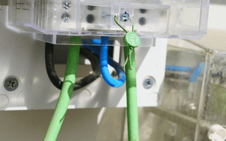 Close-up image showing a white electrical box and its green wire connections.