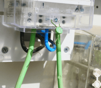 Close-up image showing a white electrical box and its green wire connections.