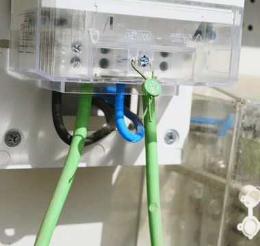 Close-up image showing a white electrical box and its green wire connections.